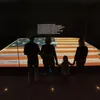 Visitors look at the Star Spangled Banner. It is dimly lit in its gallery at the museum.