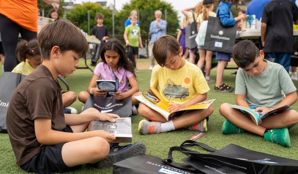 A group of children sit on the grass to read silently to themselves