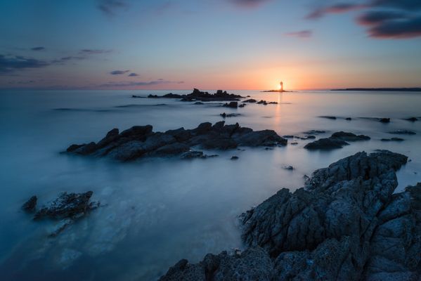 Sunset at the "Mangiabarche" (eat boats in English) lighthouse, Calasetta, Sant’Antioco Island, Sardinia, Italy. These rocks, which like the crests of dinosaurs emerge from the water, give a good idea of ​​how treacherous this stretch of sea is for boats. The lighthouse, in fact, owes its name to the numerous stranded and sunken near it.