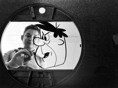 An unidentified Hanna-Barbera Productions painter works on an animation cel of Fred Flintstone. THE FLINTSTONES and all related characters and elements © & ™ Hanna-Barbera. (s16)
