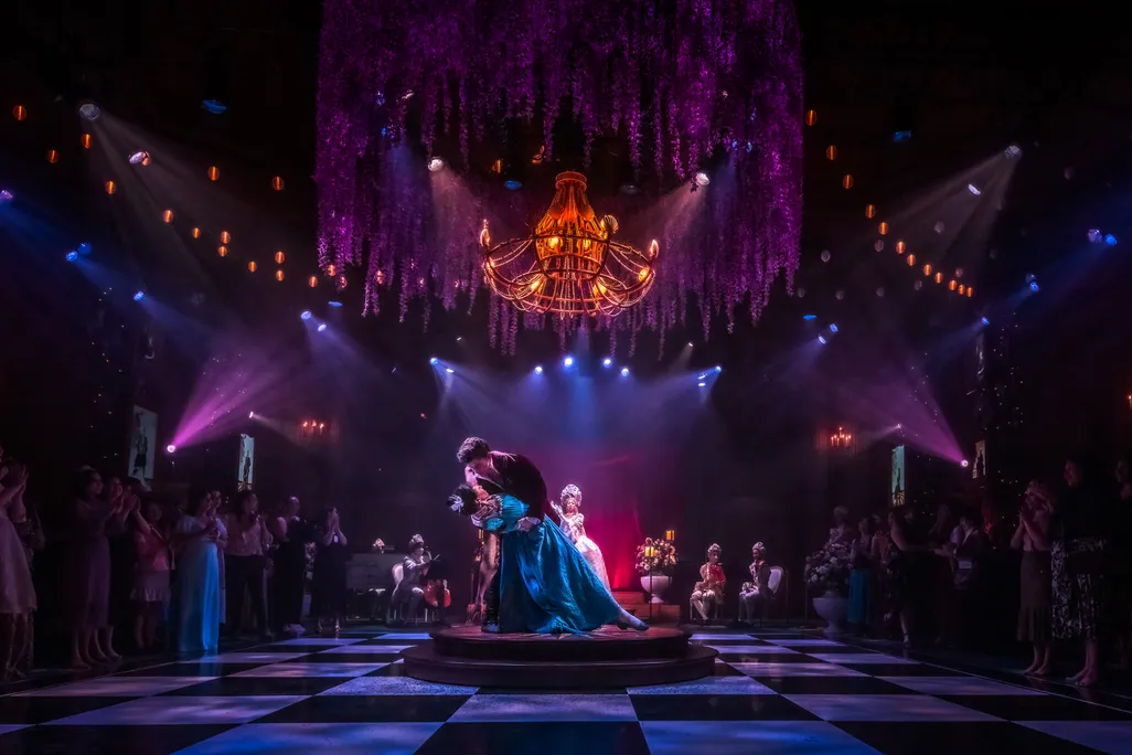 couple in Regency attire doing a dip in the middle of a dramatically lit ballroom