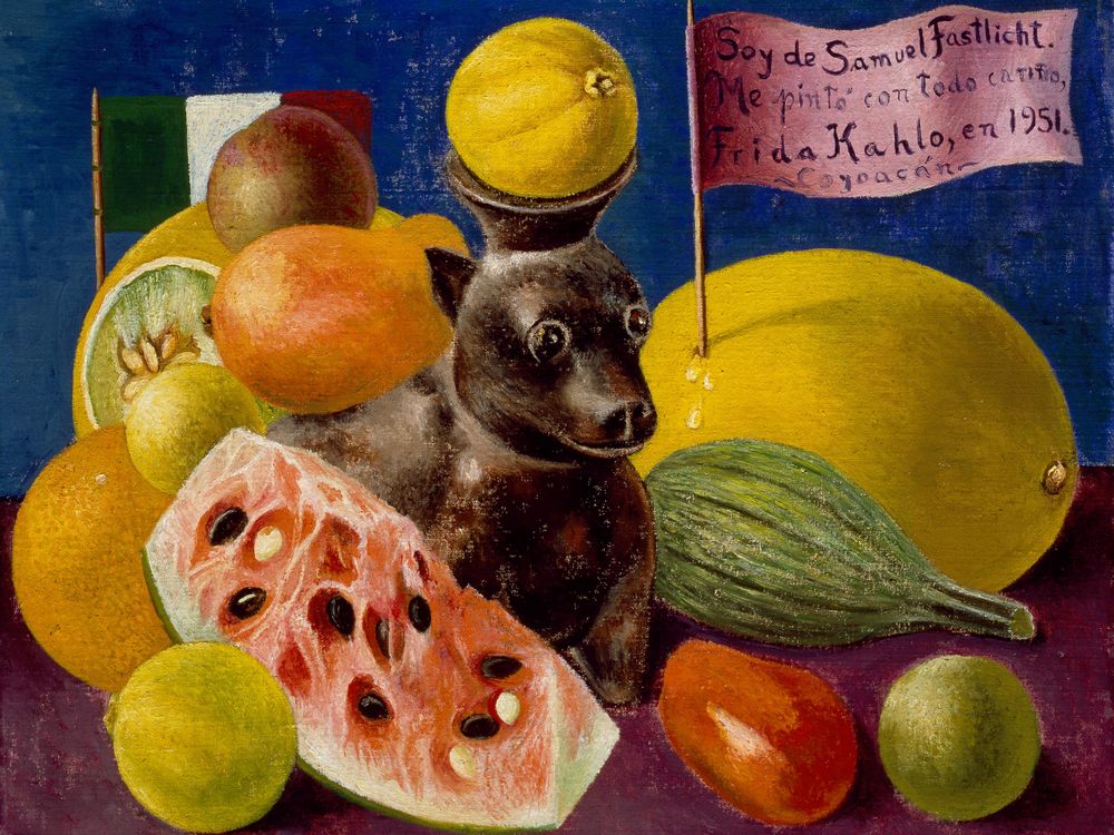 A still life with a small dog-shaped vessel in the center, holding a yellow fruit on its head; surrounded by watermelon cut open, other colorful fruits, a blue background and a flag with a phrase Soy de Samuel Fastlicht