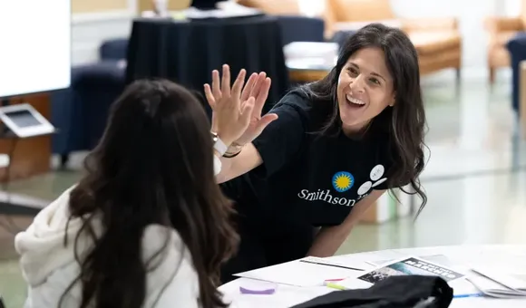 Woman with Smithsonian shirt gives girl a high five