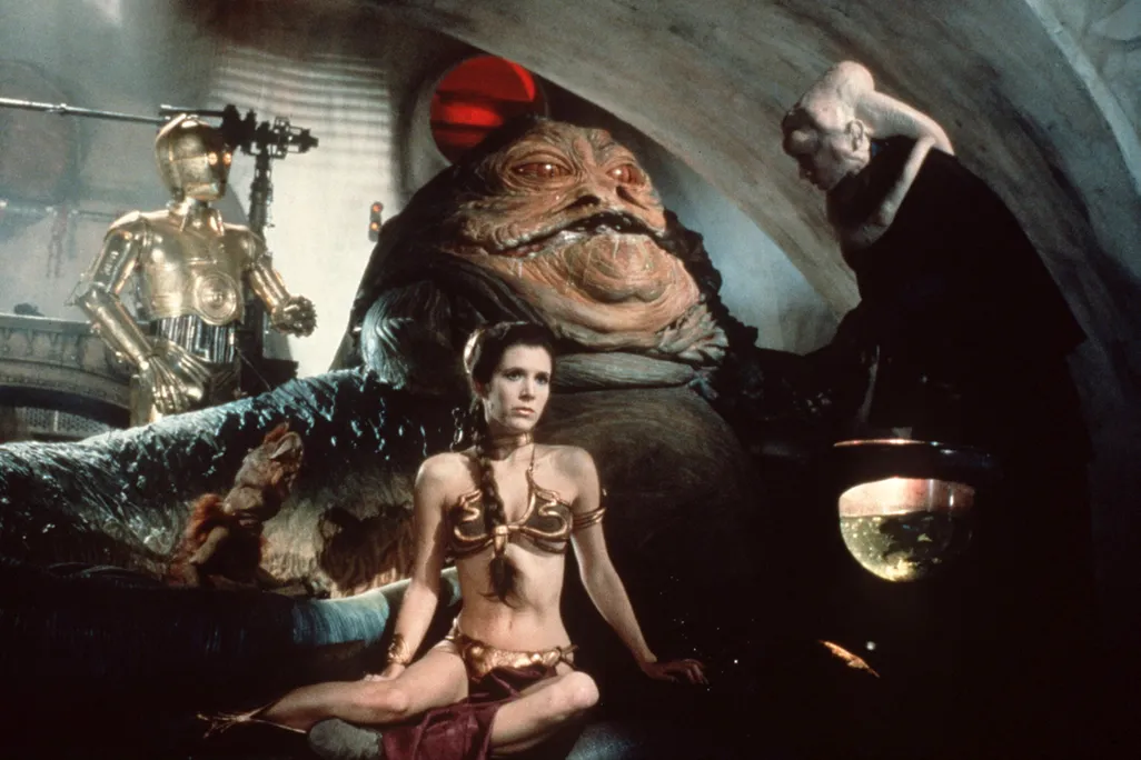 Woman wearing a gold bikini in front of a large slug-like creature