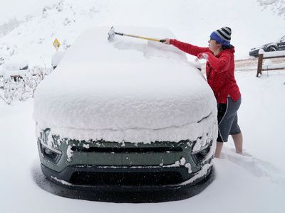 A person clears snow off their car in February 2023 after a snowstorm in Provo, Utah.