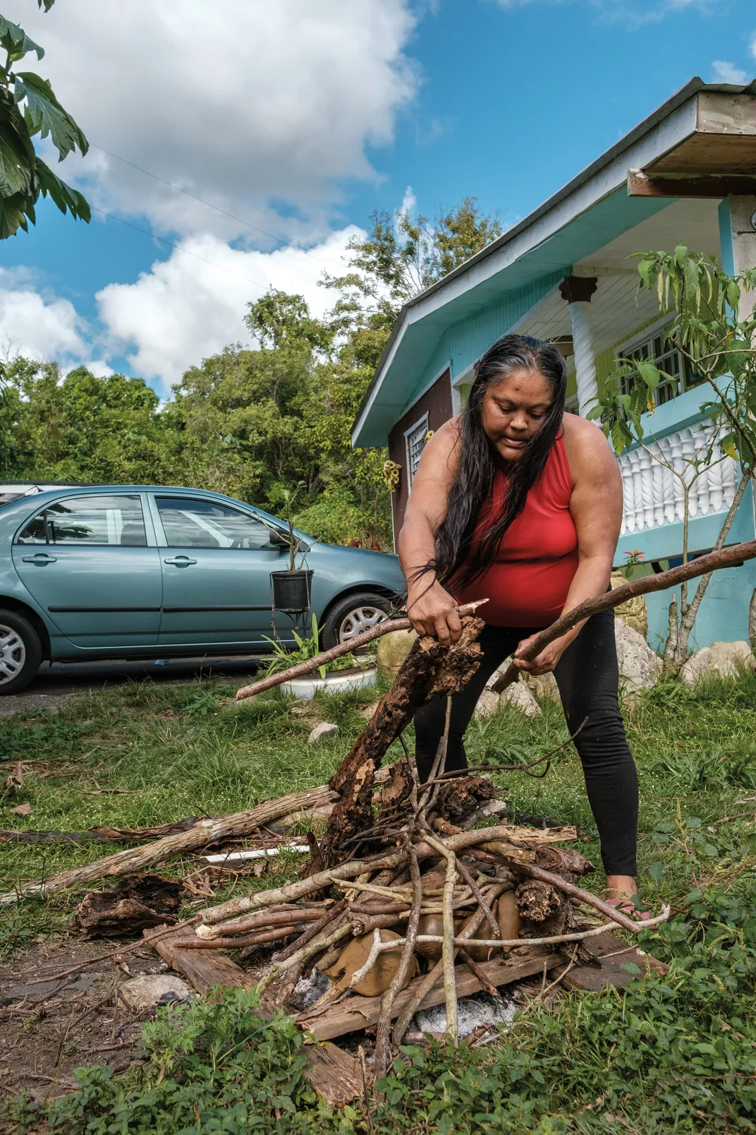 a woman in a red shirt lays firewood down on the ground