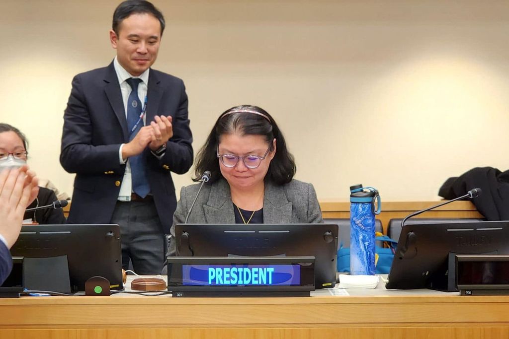 woman smiles at desk as people applaud