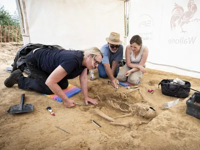 Archaeologists carefully brush away dirt from the skeleton.