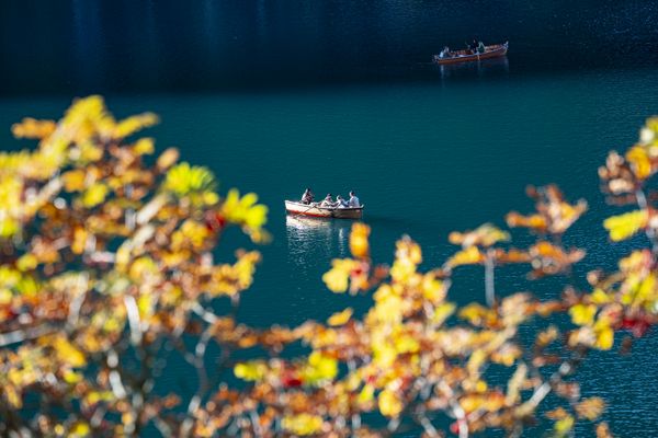Tourists float languidly on Lago di Braies in the Dolomites, Italy, in the late. afternoon. thumbnail