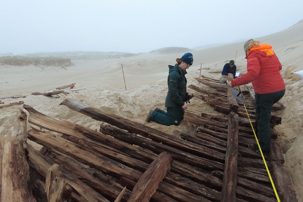 Archaeologists working on shipwreck timbers in sand