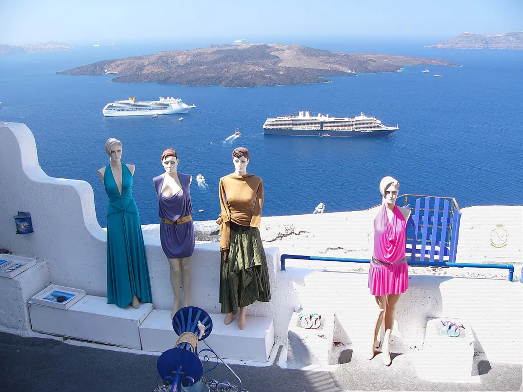 Colorfully clad mannequins are seemingly uninterested in the view of the harbor in Santorini.