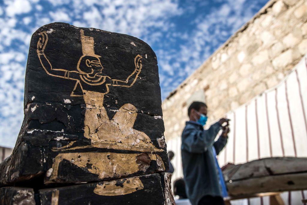 Tourist stands next to wooden coffin unearthed at Saqqara