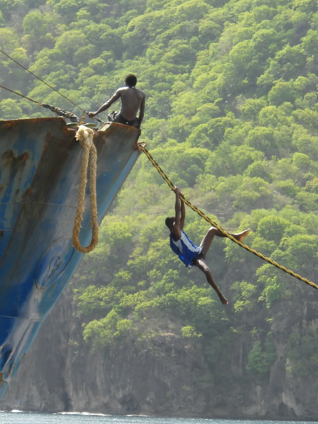 Adventurous teenagers explore a rusty ship near cliffs.