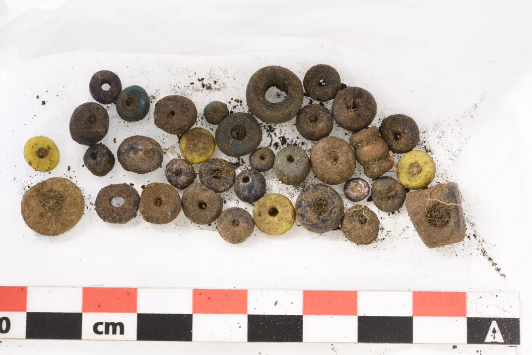 Dirty beads against a white backdrop with a measuring stick underneath