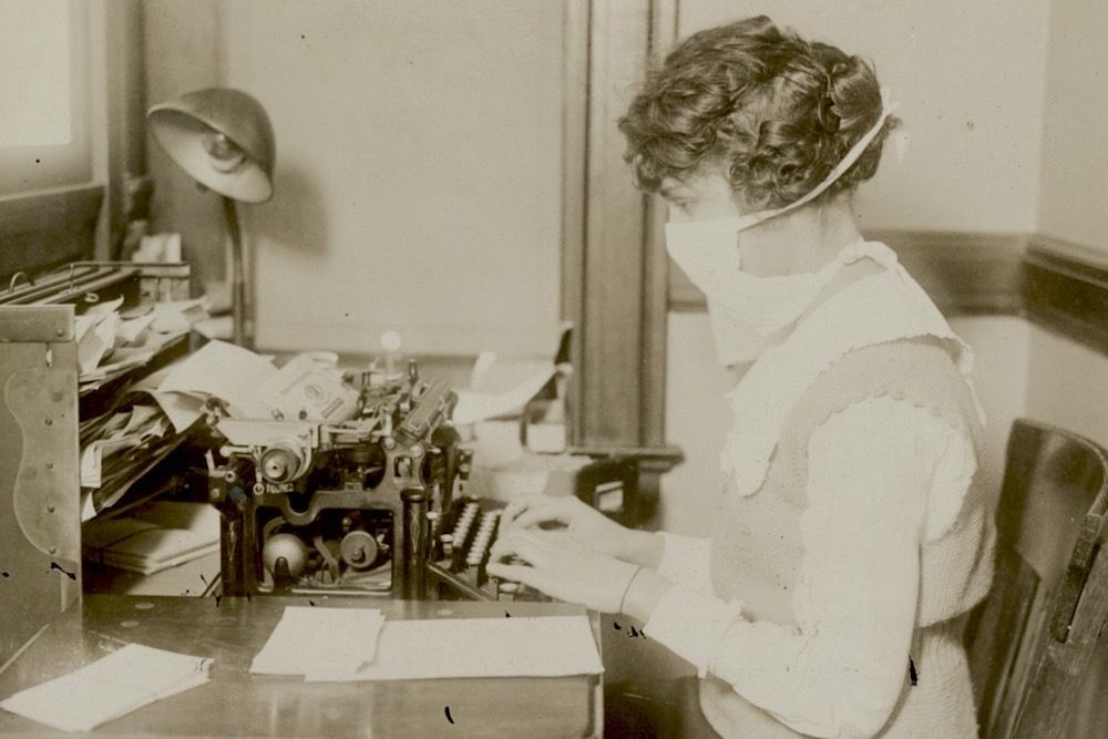 woman typing wearing a mask