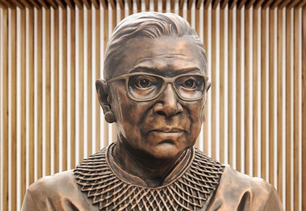 A close up of the bronze sculpture of RBG's face, with her distinctive collar and square glasses