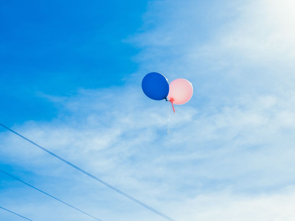 Balloons floating in sky above power lines