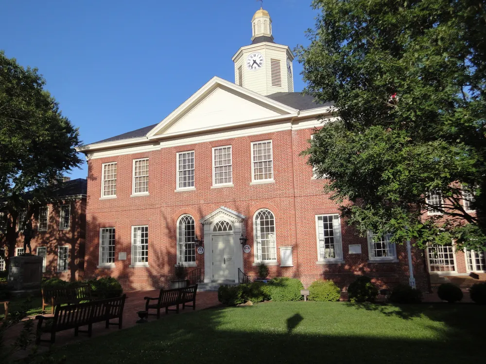 A red brick old-fashioned courthouse in front of a blue sky and a manicured green lawn