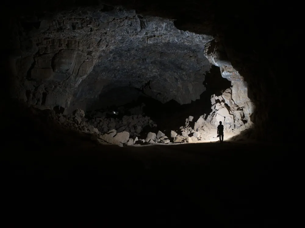 a person stands in a dimly lit cave