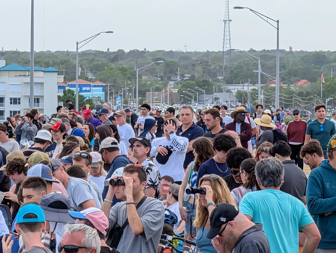 a large crowd of people, some with binoculars