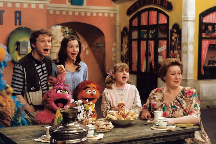 "Ulitsa Sezam" actors singing on set, from left to right: Alexander Lyrchikov (father Sasha), Ekaterina Strizhenova (mother Nina), Muppets Businka and Kubik with Katya Mikhailovskaya (young Katya), and Maria Aronova (Aunt Dasha)
