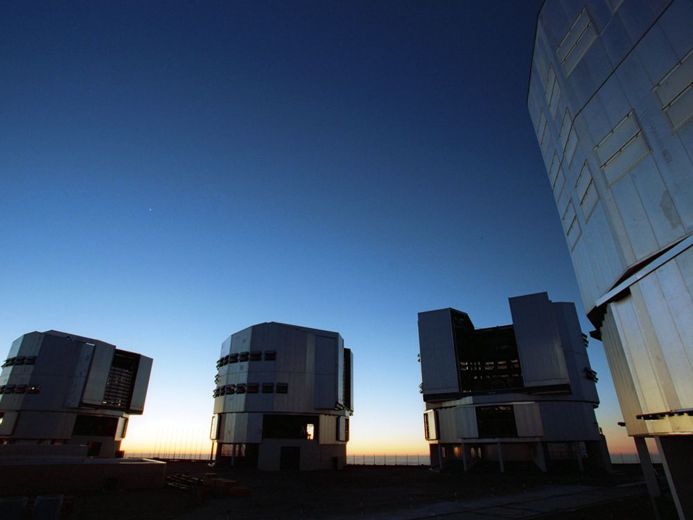 Four large telescopes below an evening sky