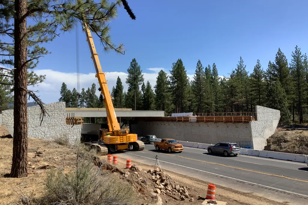 Construction vehicles working on an overpass above a highway