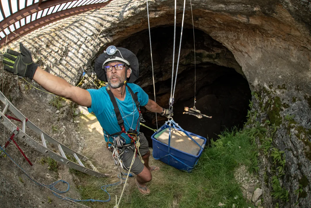 Doug Warner, seasoned climber and the rope safety leader for the 2024 expedition, delicately transfers a box of fossils to the surface.