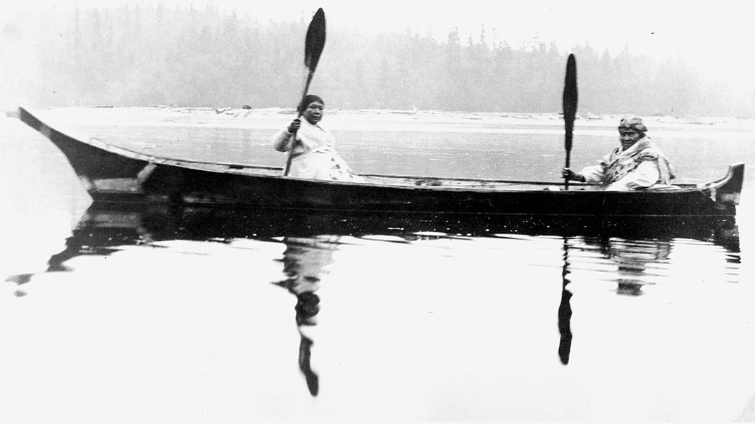 Two people in a canoe out on the water. Black-and-white archival photo.