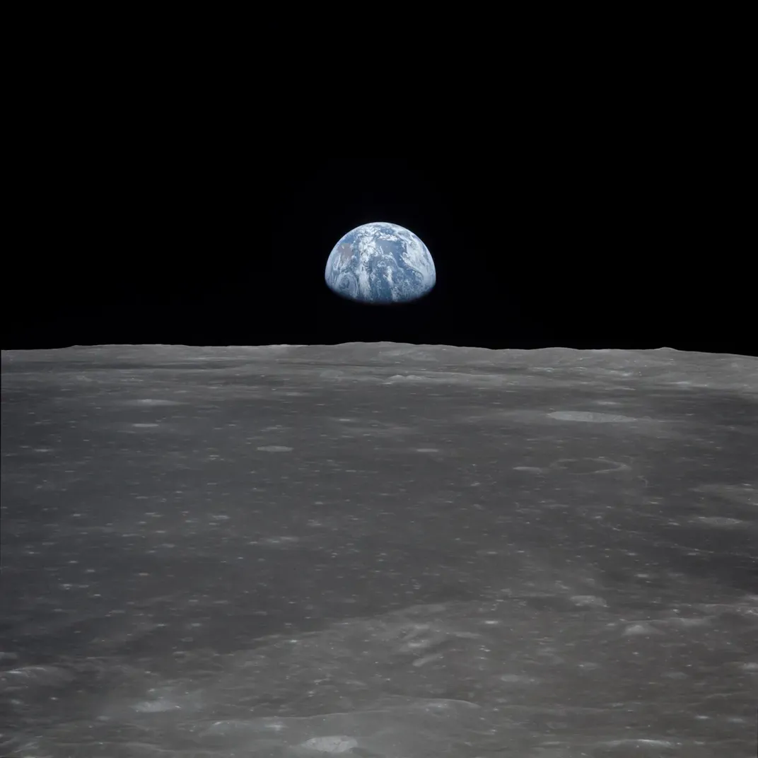 Earth rises in darkness over the moon's terrain