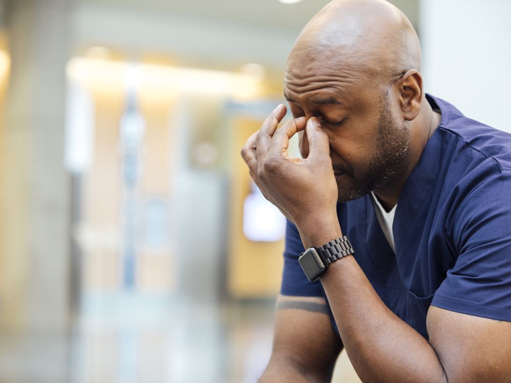 A stressed person pinches the bridge of their nose