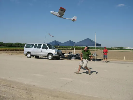 A researcher launches a drone while a backup pilot stands by with radio controls in hand