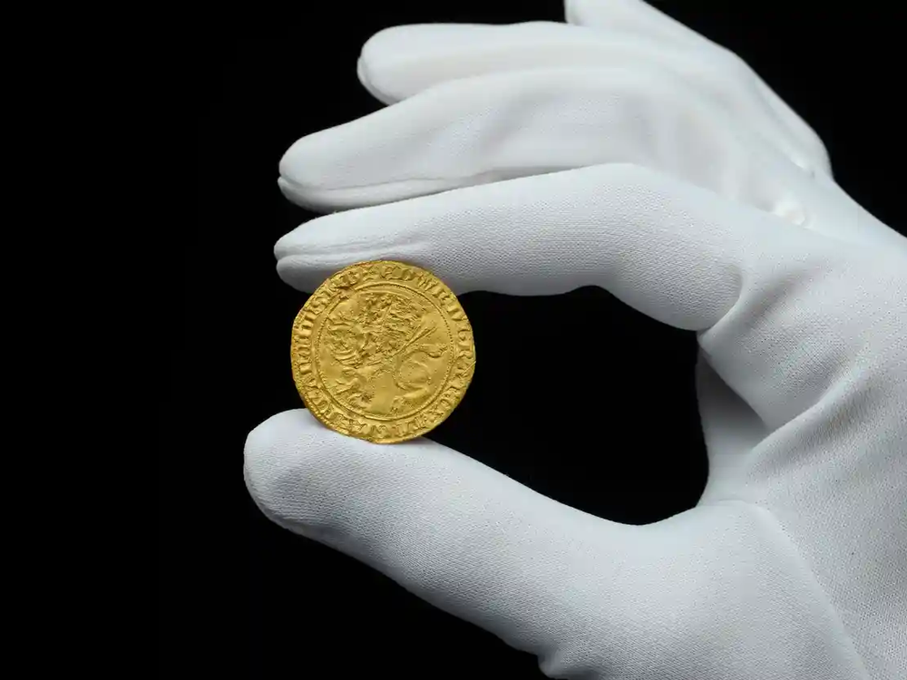 gold coin being held by gloved hand