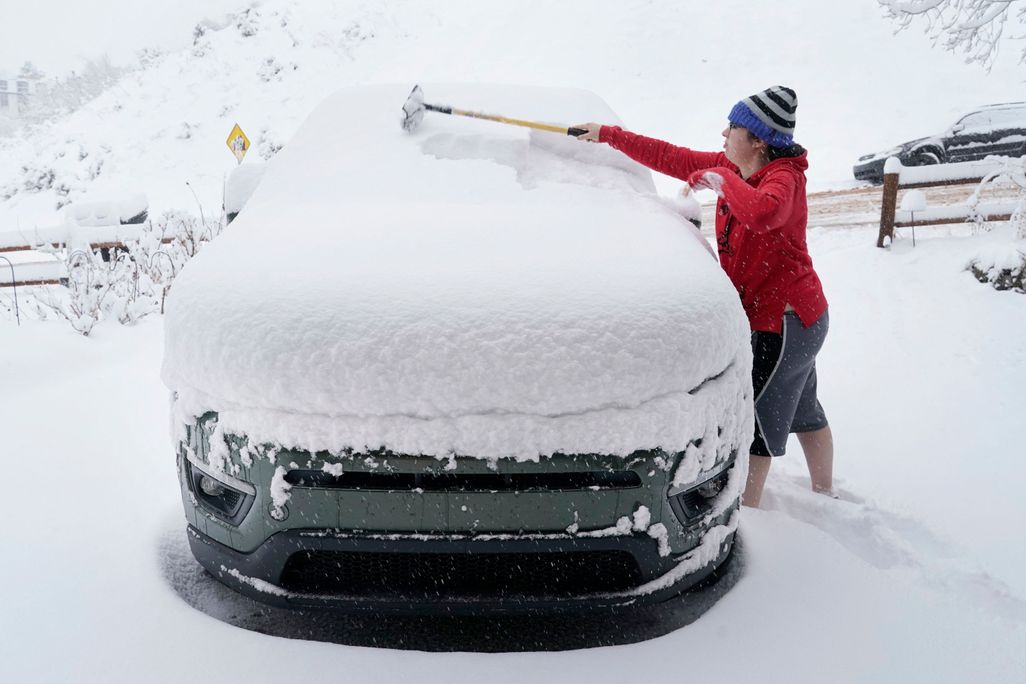A person clears off their car of snow