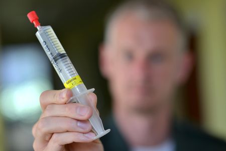 Ketamine syringe, 10mg held by a healthcare professional.
