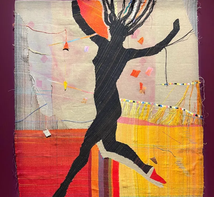 A black silhouette of a jumping woman against a colorful fabric background.