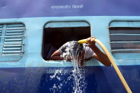 A man cools off using a water pipe at a train station in Allahabad, India. 