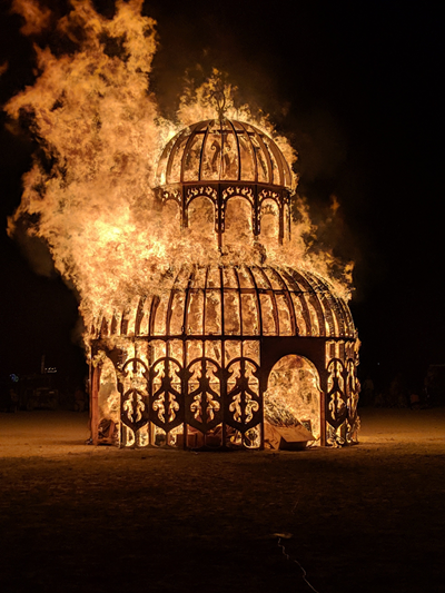 A photograph of a wooden temple burning from a fire.