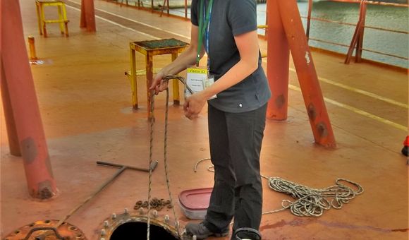 The author lowers a net into a topside ballast water tank to sample marine plankton and zooplankton