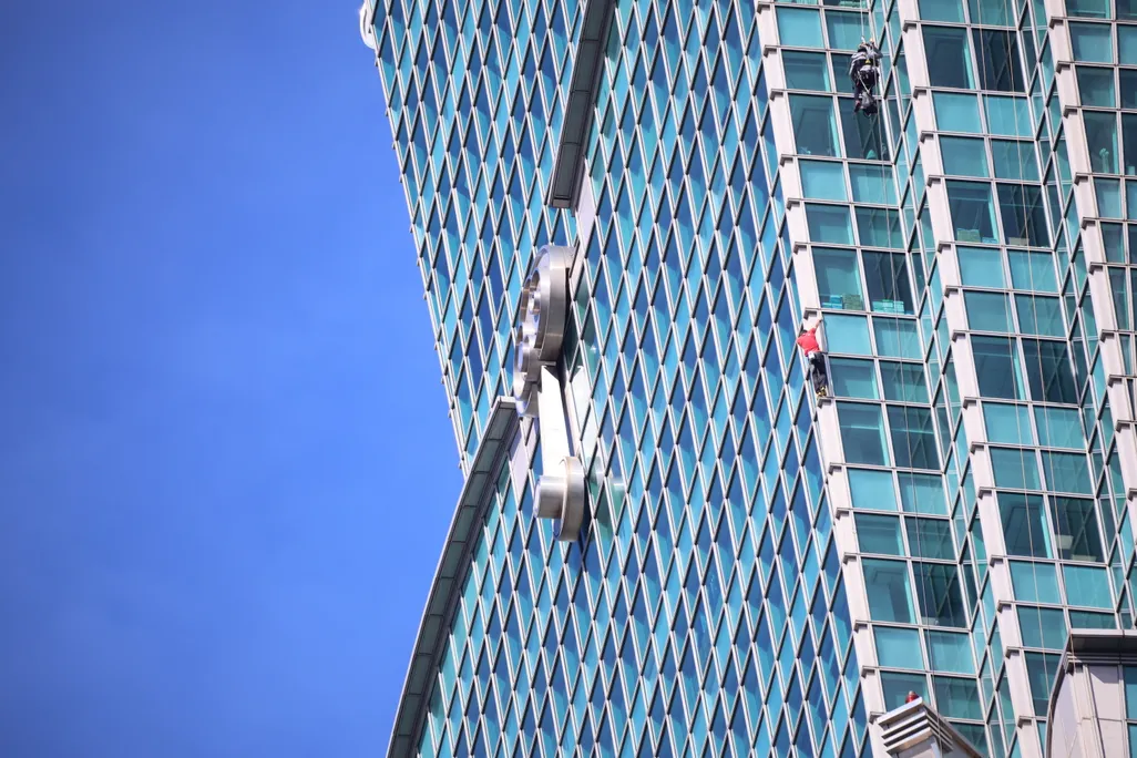 A person in a red shirt climbing a skyscraper