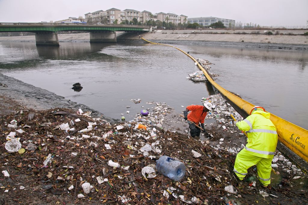 Trash in a river is getting picked up by two workers