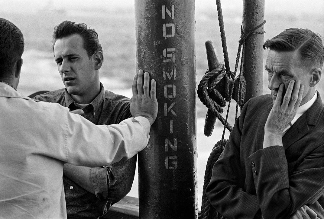 Men in conversation near a no smoking sign.