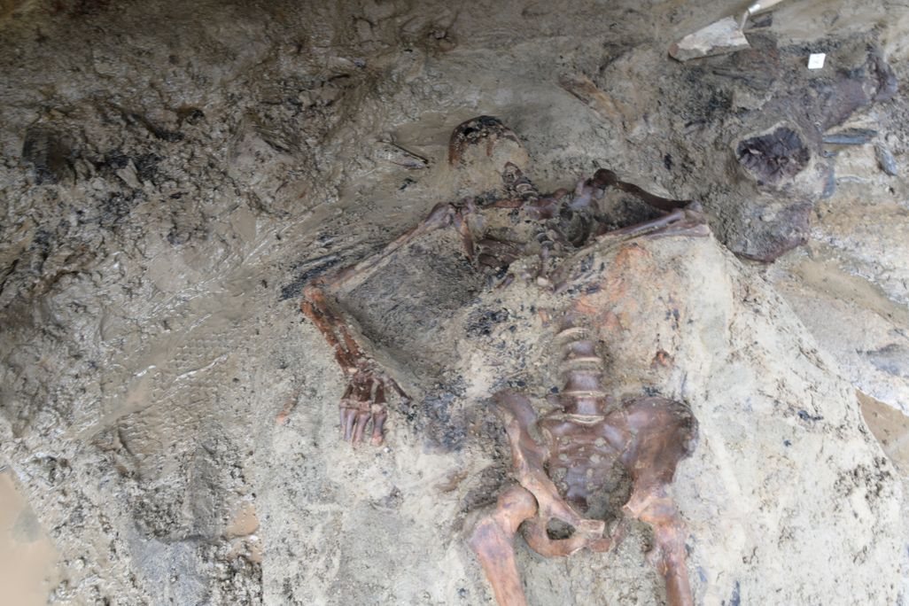 A skeleton lying half-encased in dirt and mud