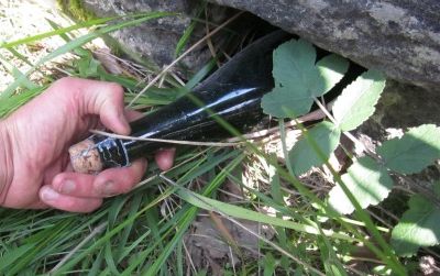 A hidden treasure–a bottle of Normandy apple cider stashed eight months earlier–is withdrawn from a hole in a rock wall in France’s Dordogne Valley. It was replaced with a Chimay Belgian ale. Want to play the game? Read this post for instructions.