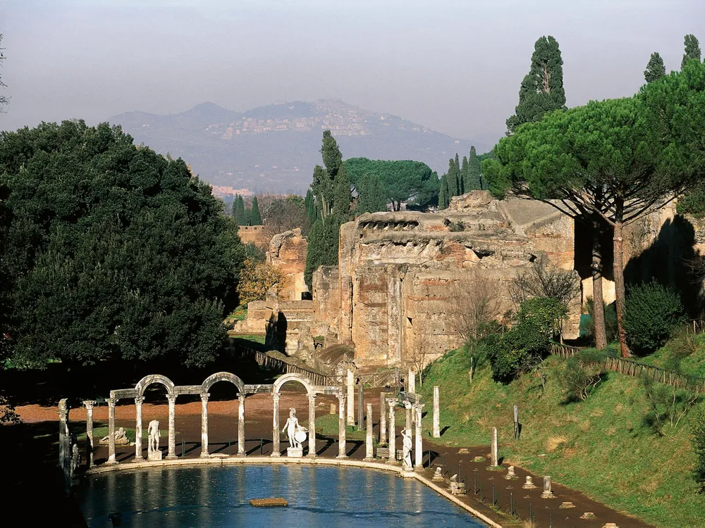 A view of a shallow pool of water with columns and crumbling structures extending behind