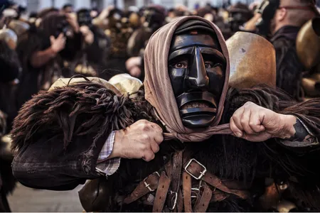 Loaded with leather and sheepskins, Salvatore Gungui tightens his headscarf. Although only men dress as Mamuthones, the scarf adds a feminine element.