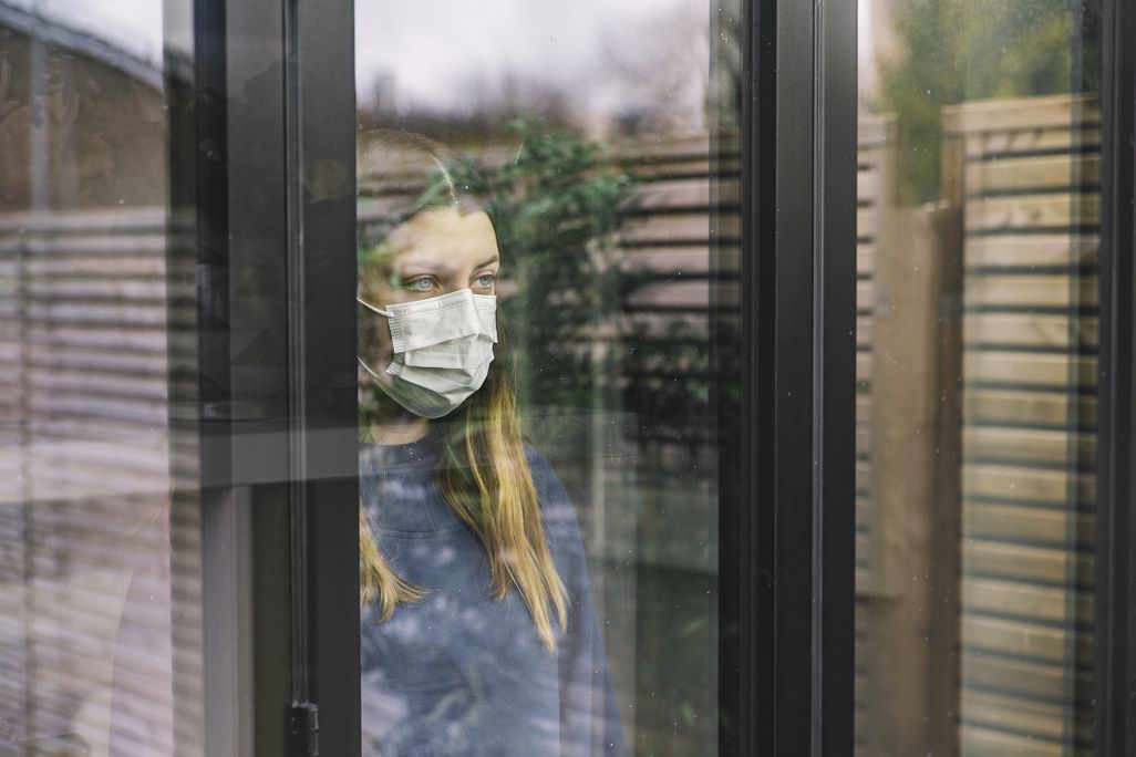 Woman wearing mask stares out a window
