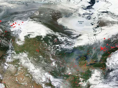 This satellite image shows active fires (in red) and gray smoke particles wafting over parts of eastern Canada and the United States.&nbsp;