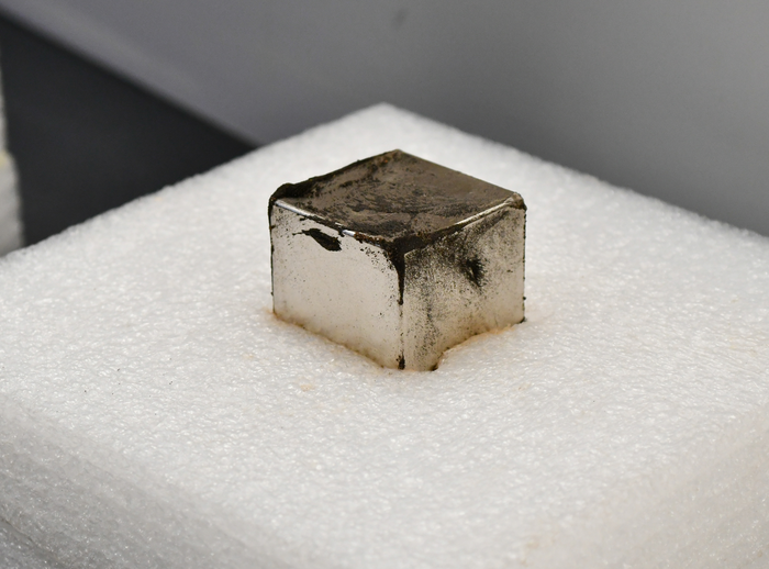 An image of meteorite dust resting against a cube-shaped magnet