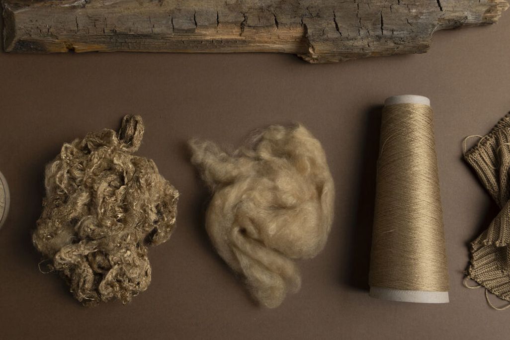 An overhead view of a piece of wood next to some yarn and knitted fabric